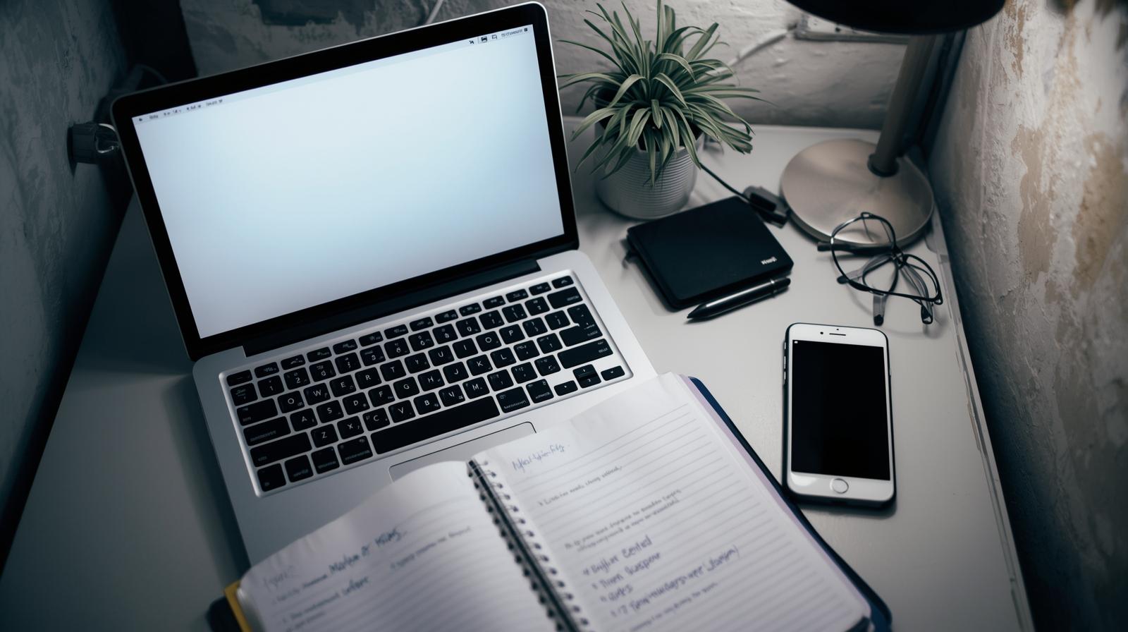 Laptop with notebook and phone setup for implementing crisis legal team workflow guide and response protocols